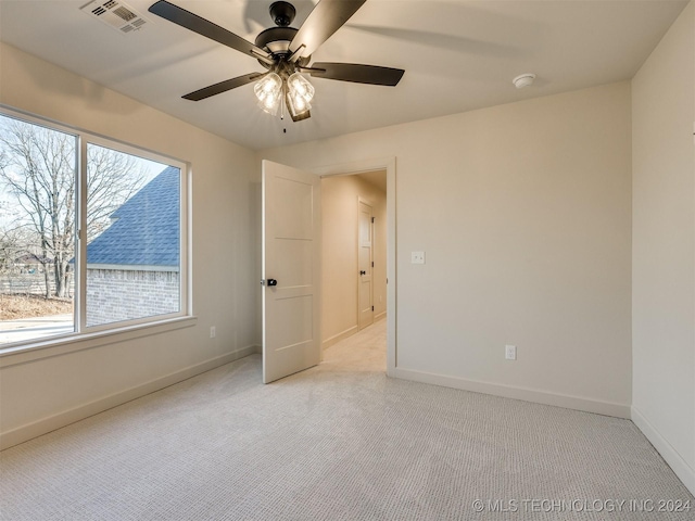 empty room with a wealth of natural light, ceiling fan, and light colored carpet