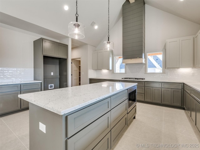 kitchen featuring light stone counters, appliances with stainless steel finishes, a center island, and light tile patterned floors