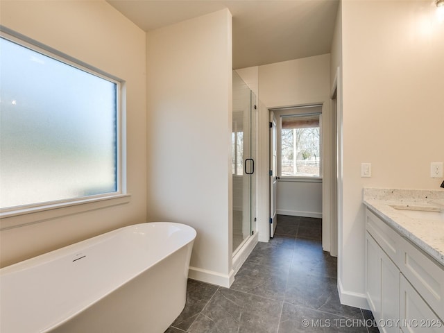 bathroom with a shower stall, a freestanding bath, vanity, and baseboards