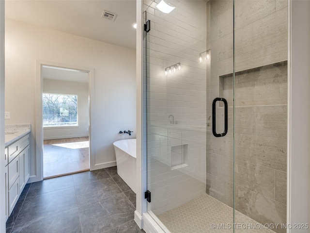 full bathroom featuring vanity, baseboards, visible vents, a stall shower, and a freestanding bath