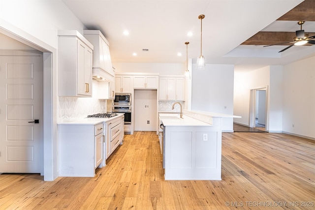 kitchen featuring ceiling fan, light wood-style flooring, light countertops, appliances with stainless steel finishes, and decorative backsplash