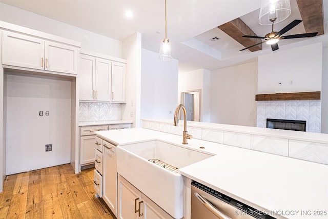 kitchen featuring light wood-style flooring, a sink, dishwasher, tasteful backsplash, and pendant lighting