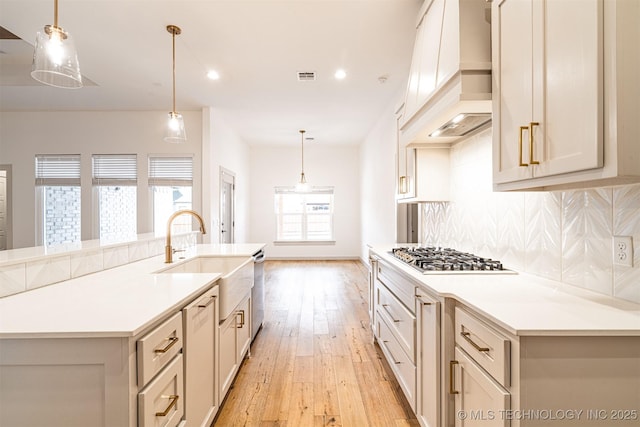 kitchen featuring custom exhaust hood, stainless steel appliances, visible vents, decorative backsplash, and light wood-style floors