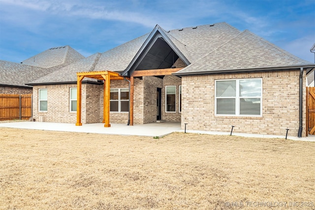 back of property featuring a patio, brick siding, roof with shingles, and fence