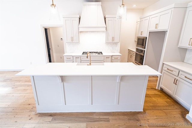 kitchen with stainless steel appliances, light wood finished floors, backsplash, and custom exhaust hood