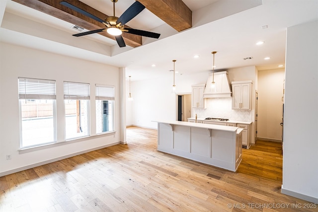 kitchen featuring premium range hood, baseboards, light countertops, light wood finished floors, and tasteful backsplash