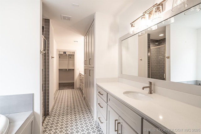 bathroom featuring visible vents, a spacious closet, a shower stall, and vanity