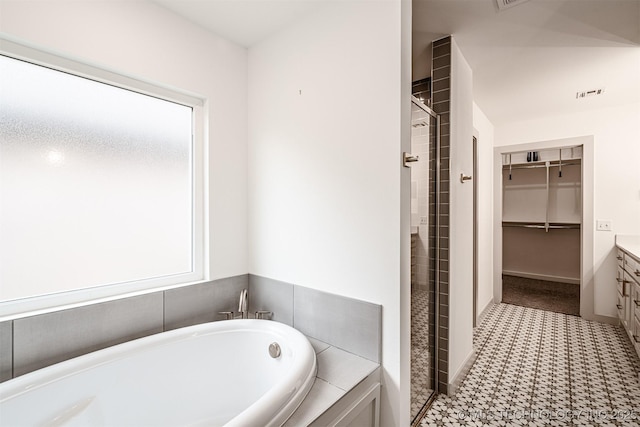 bathroom featuring visible vents, vanity, a spacious closet, a shower stall, and a bath