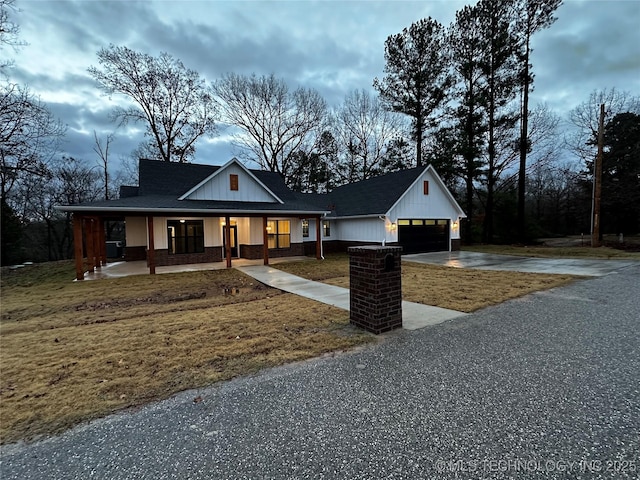 modern farmhouse style home with a front lawn, a porch, and a garage