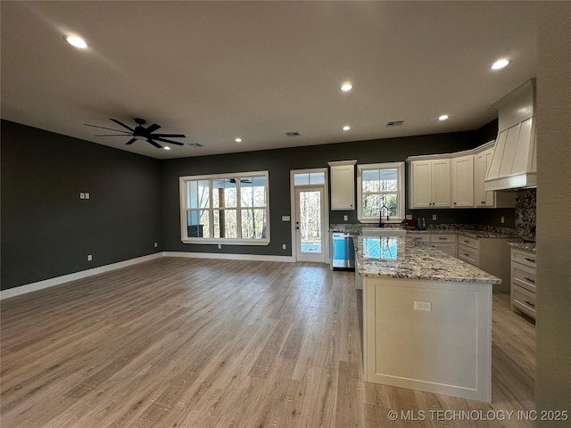 kitchen featuring white cabinets, sink, decorative backsplash, ceiling fan, and a kitchen island