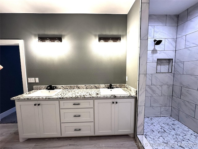 bathroom featuring vanity, wood-type flooring, and tiled shower