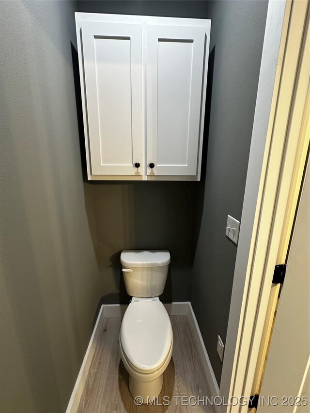 bathroom with hardwood / wood-style flooring and toilet