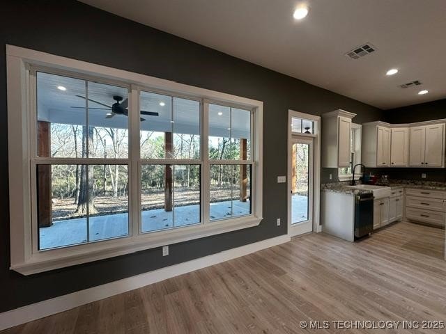 kitchen featuring light wood-type flooring, white cabinetry, sink, and a wealth of natural light