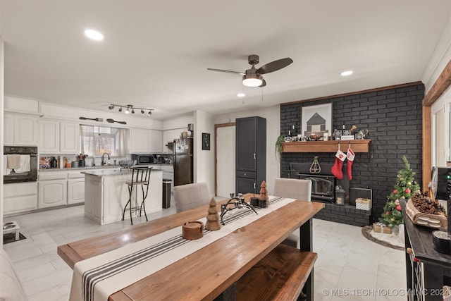 dining space featuring a wood stove, ceiling fan, and sink