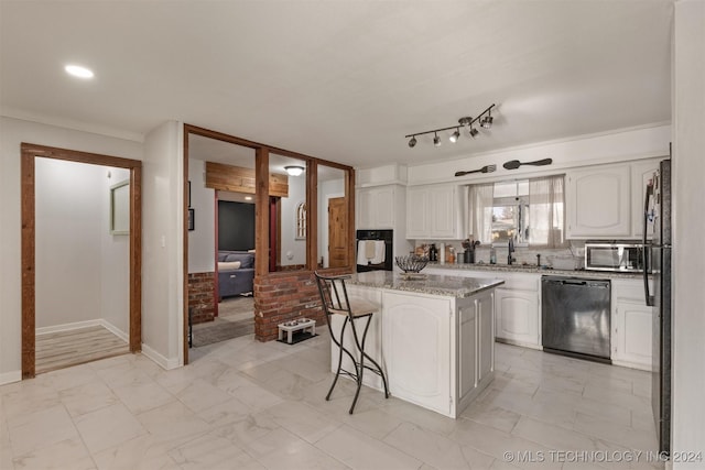 kitchen with a breakfast bar area, white cabinetry, a kitchen island, and black appliances