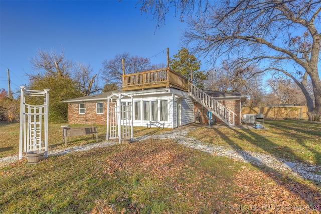 rear view of house featuring a lawn, a sunroom, and a balcony