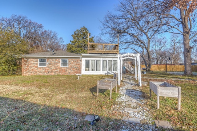 rear view of house with a sunroom, a yard, and a balcony