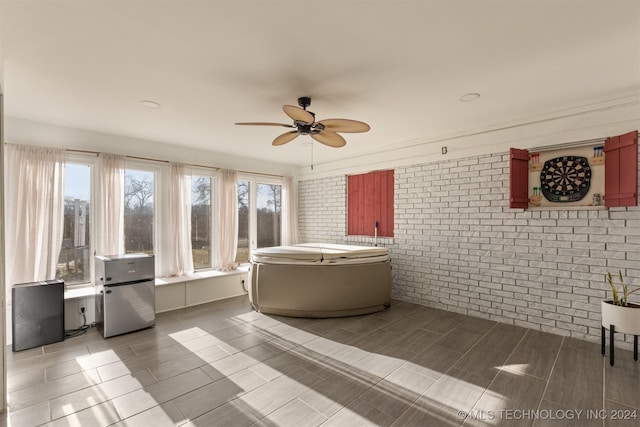 bathroom featuring ceiling fan and brick wall