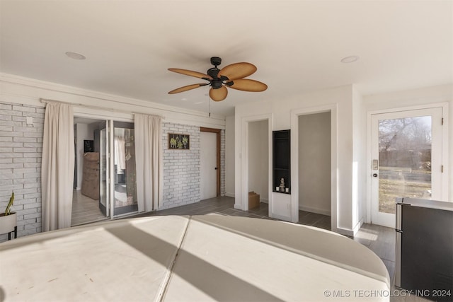 bedroom with ceiling fan and brick wall