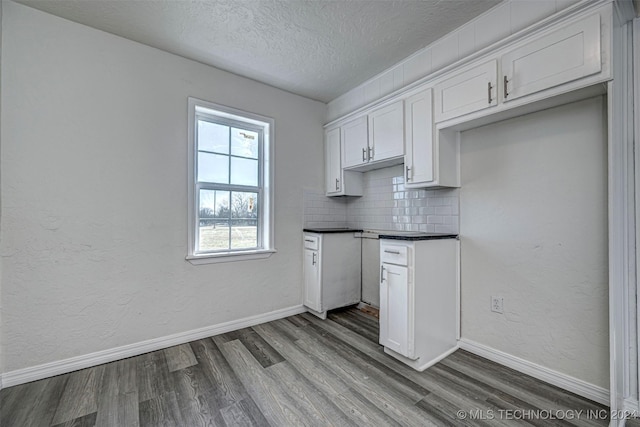 kitchen featuring white cabinets, hardwood / wood-style floors, a textured ceiling, and tasteful backsplash