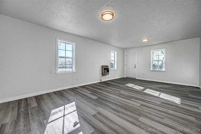 empty room featuring heating unit, dark wood-type flooring, and a textured ceiling