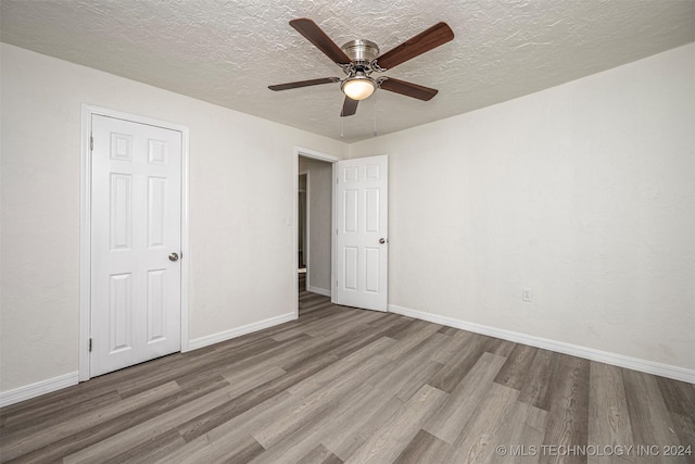 unfurnished bedroom featuring wood-type flooring, a textured ceiling, and ceiling fan