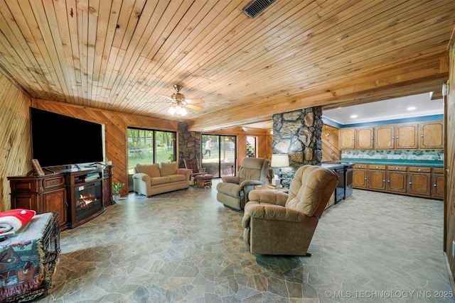 living room with a stone fireplace, wooden walls, ceiling fan, and wooden ceiling