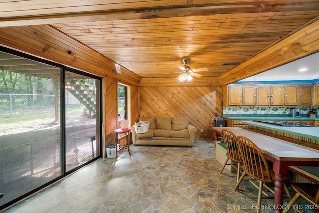 interior space featuring ceiling fan, wood walls, and wood ceiling