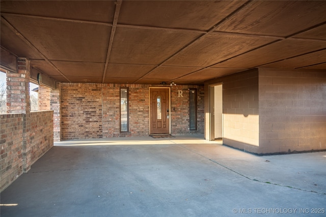 exterior space featuring wood ceiling and brick wall