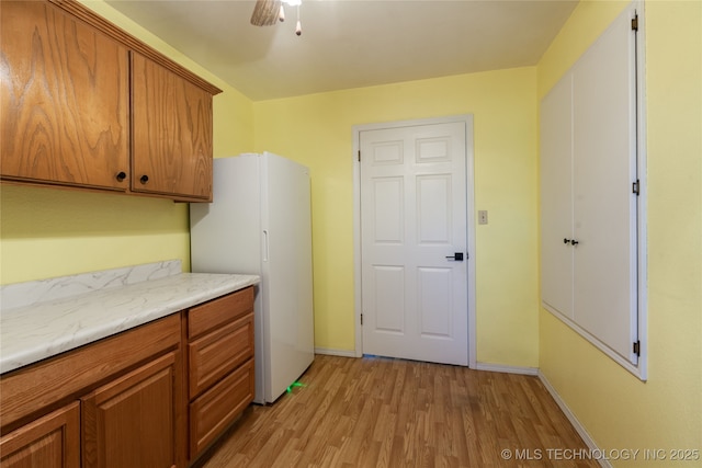 laundry area with light wood-type flooring and ceiling fan