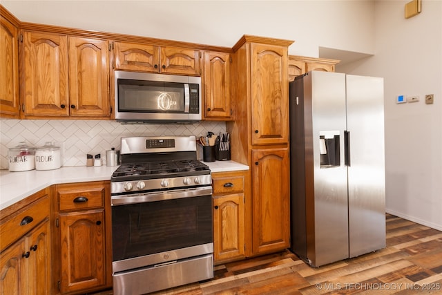 kitchen with decorative backsplash, dark hardwood / wood-style flooring, and appliances with stainless steel finishes