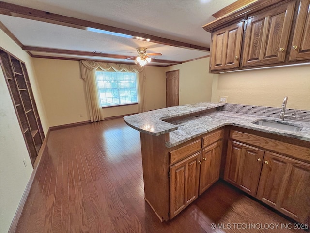 kitchen with sink, ceiling fan, dark hardwood / wood-style flooring, light stone counters, and kitchen peninsula