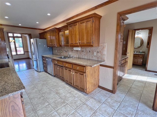 kitchen featuring appliances with stainless steel finishes, light stone counters, ornamental molding, sink, and light tile patterned flooring