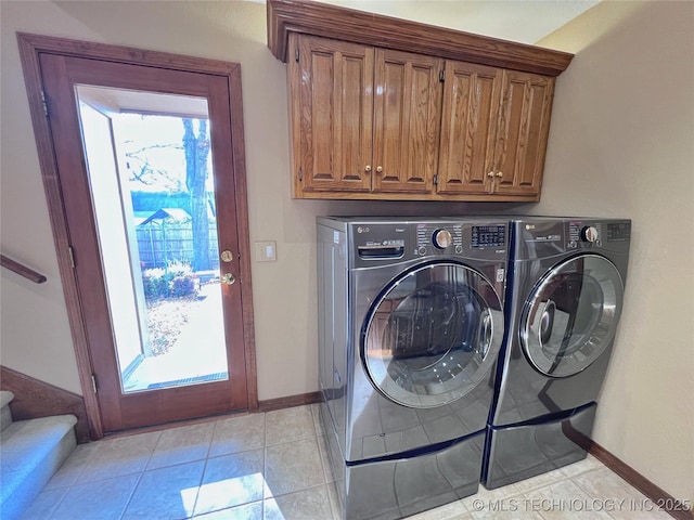 laundry area featuring washer and clothes dryer, light tile patterned flooring, cabinets, and a wealth of natural light