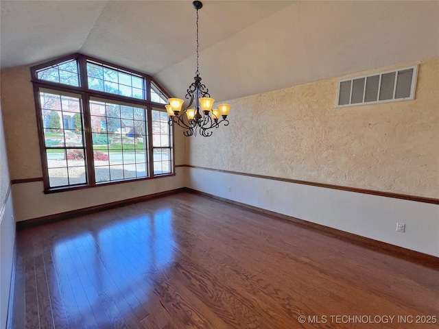 empty room featuring dark hardwood / wood-style flooring, vaulted ceiling, and an inviting chandelier