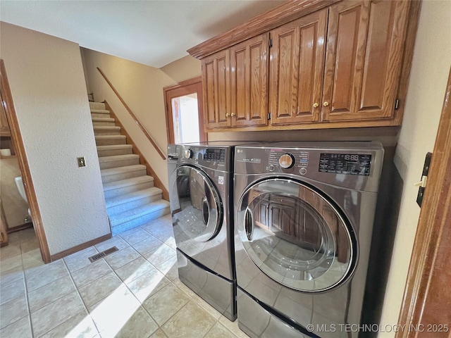 washroom featuring cabinets, independent washer and dryer, and light tile patterned floors