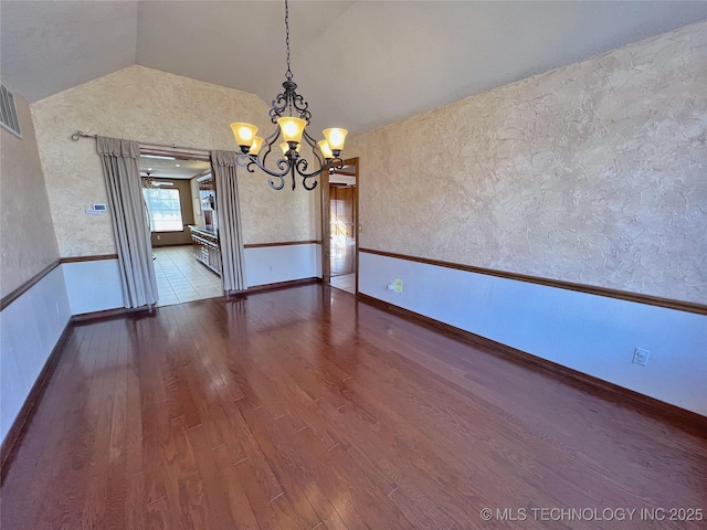 unfurnished dining area featuring hardwood / wood-style floors, vaulted ceiling, and an inviting chandelier