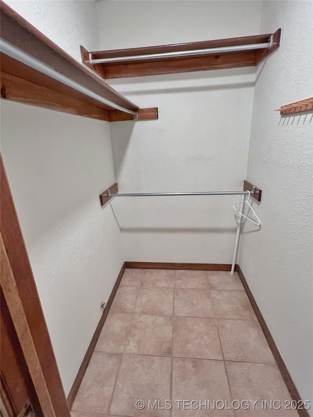 walk in closet with light tile patterned floors