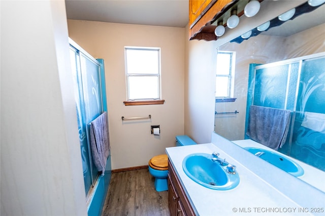 bathroom featuring wood-type flooring, vanity, toilet, and an enclosed shower