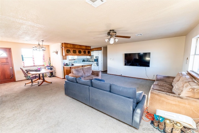 living room with a textured ceiling, light carpet, and ceiling fan with notable chandelier