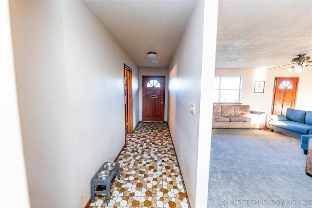 corridor with a textured ceiling and light carpet