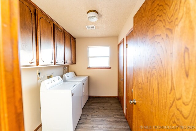 laundry area with washer and dryer, cabinets, light wood-type flooring, and a textured ceiling