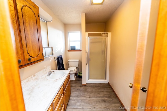 bathroom featuring vanity, wood-type flooring, a textured ceiling, and a shower with door