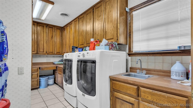 clothes washing area with washer and dryer, light tile patterned floors, and sink