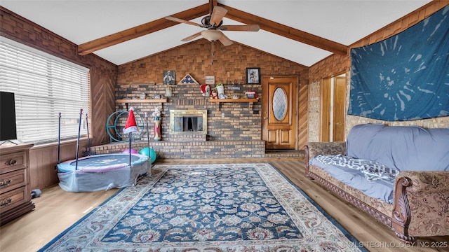 living room with hardwood / wood-style flooring, lofted ceiling with beams, ceiling fan, and brick wall