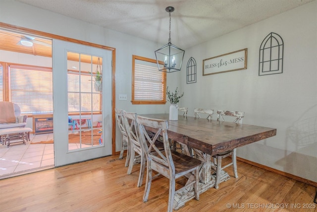 dining area with wood-type flooring, a textured ceiling, and a notable chandelier