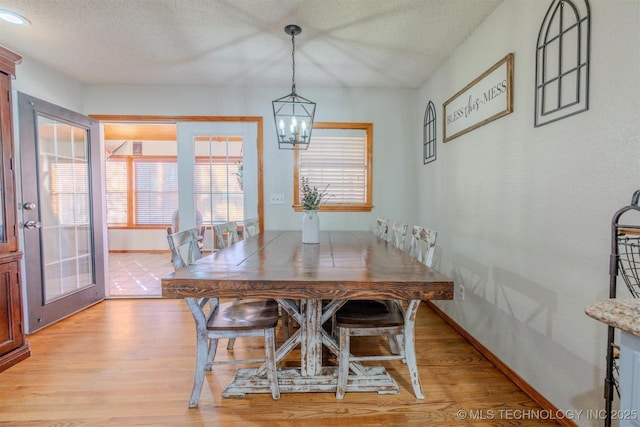 dining room featuring french doors, light hardwood / wood-style flooring, a chandelier, and a textured ceiling