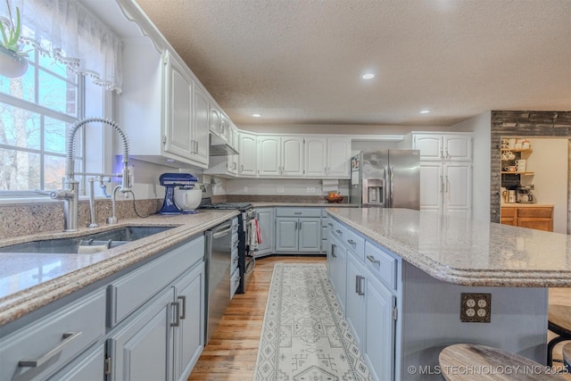 kitchen featuring a kitchen island, sink, white cabinetry, and stainless steel appliances