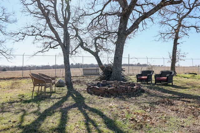 view of yard with an outdoor fire pit and a rural view