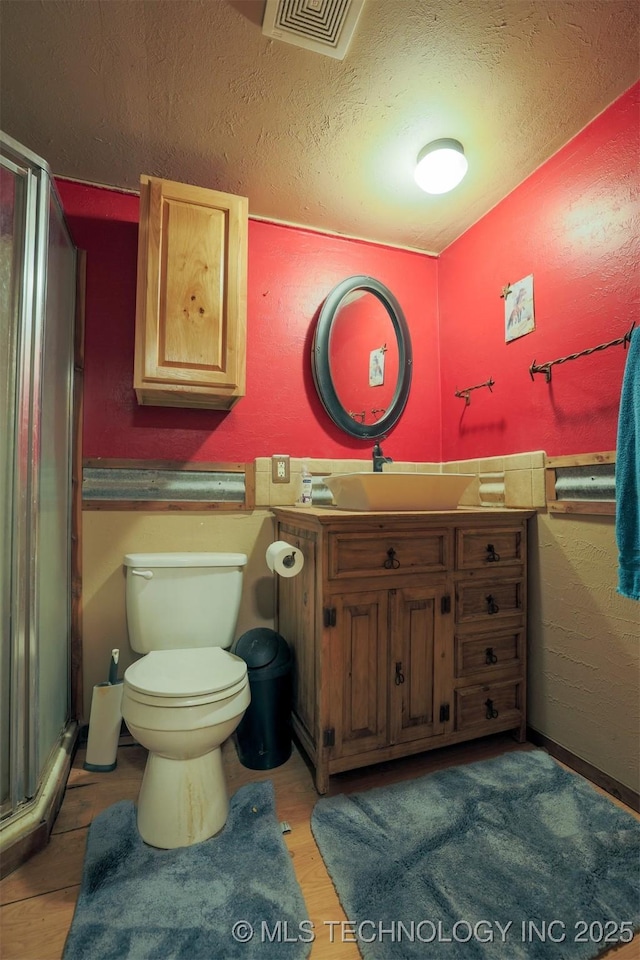 bathroom featuring a shower with door, a textured ceiling, toilet, and vanity